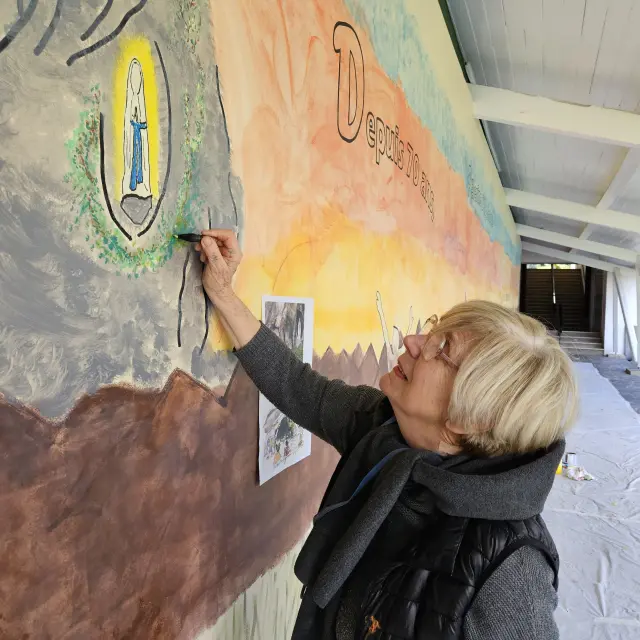 Chantal Morat entrain de peindre la grotte sur la fresque