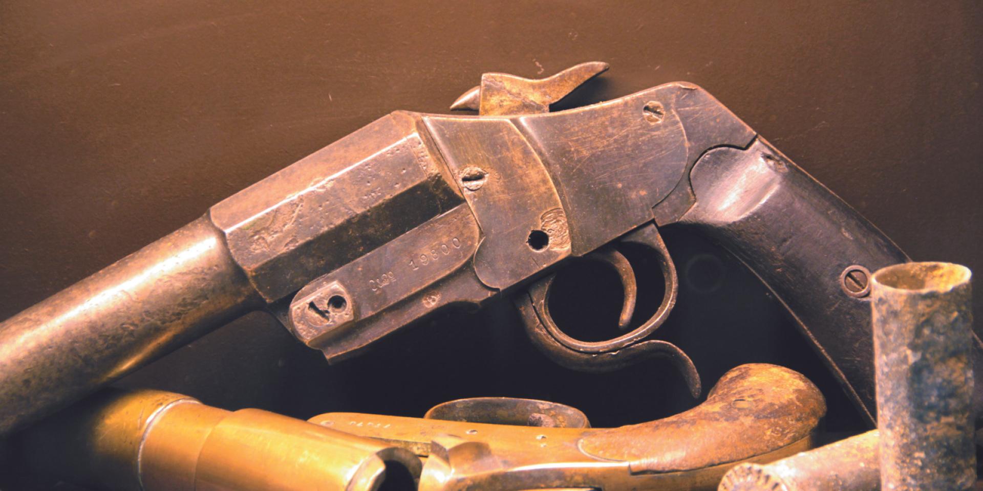 Pistolet et douilles de balles exposés sous vitrine