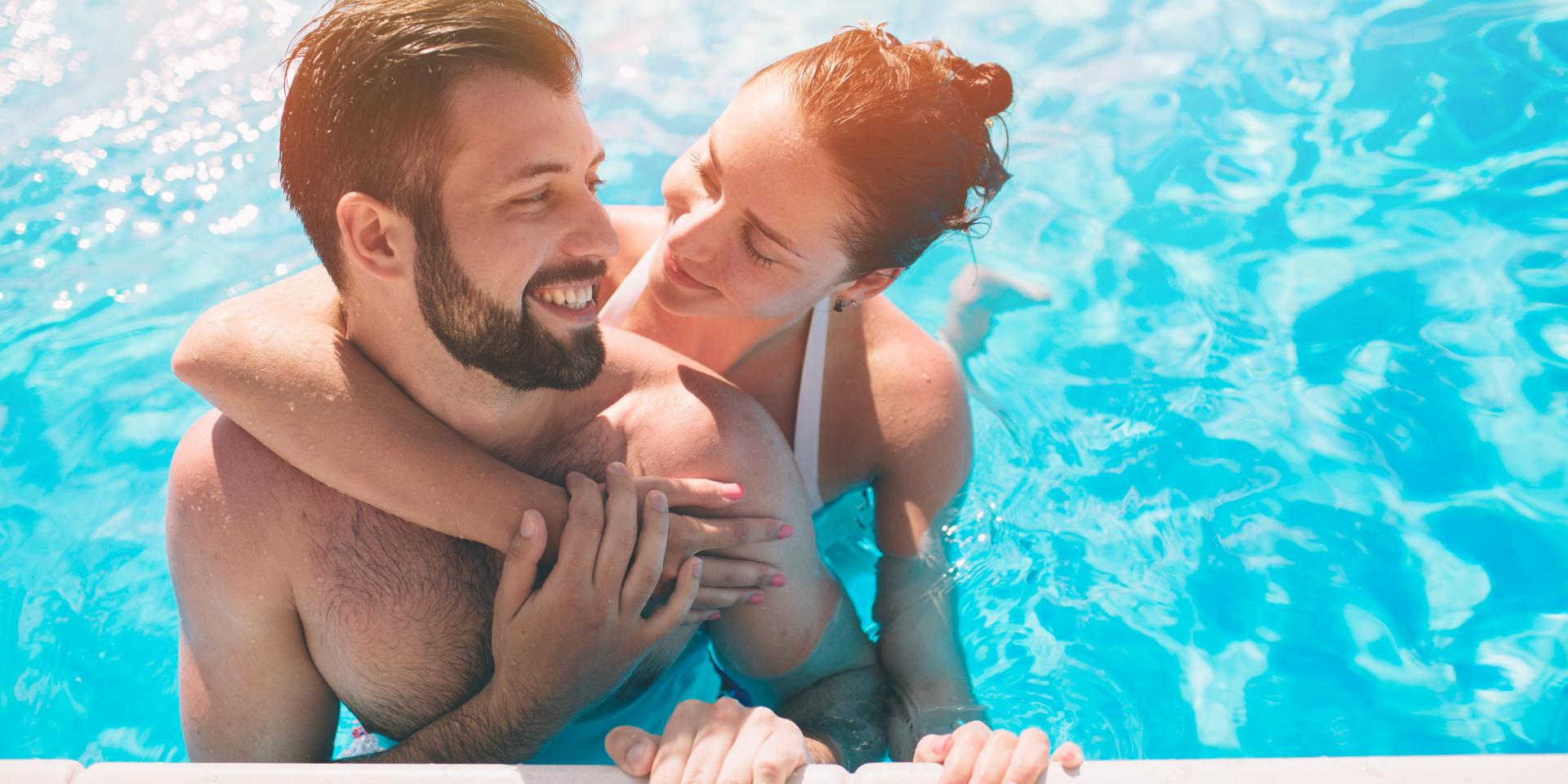 Cheerful youthful guy and lady resting while swimming pool outdoor. Couple in water.