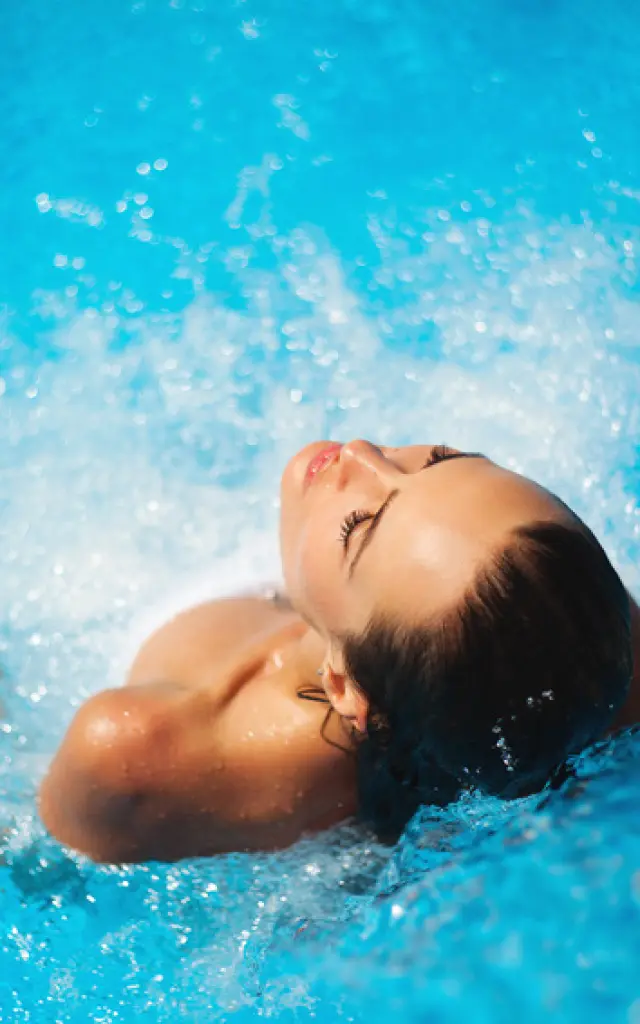 Jeune femme se prélassant dans une piscine à jets