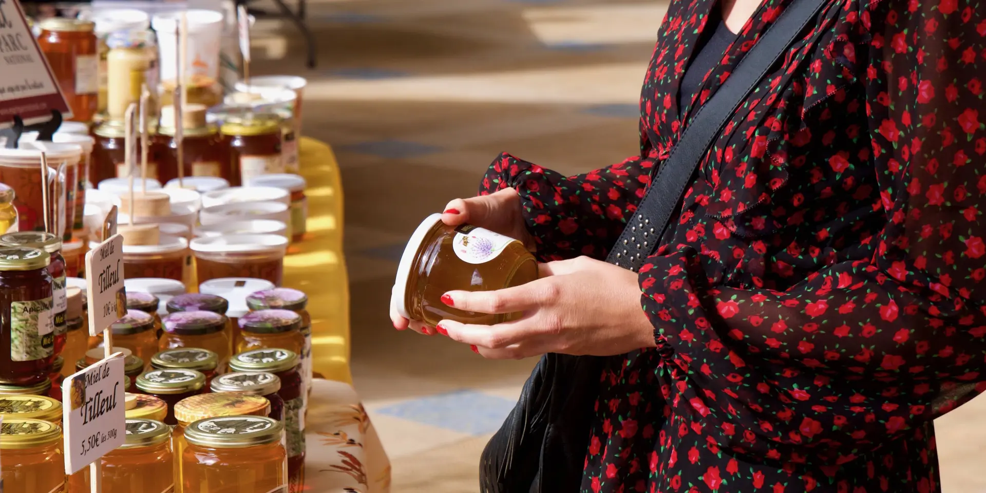 Jeune femme tenant un pot de miel lors d'un marché du terroir sous la galerie thermale de Contrexéville