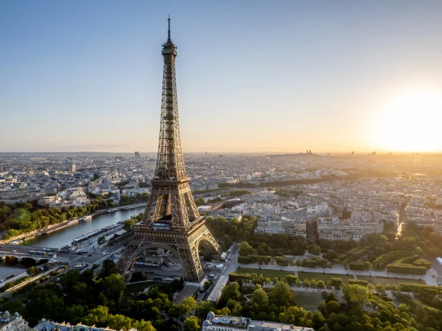 Aerial view of Paris, France, overlooking the famous Eiffel Tower, sunrise in the background.