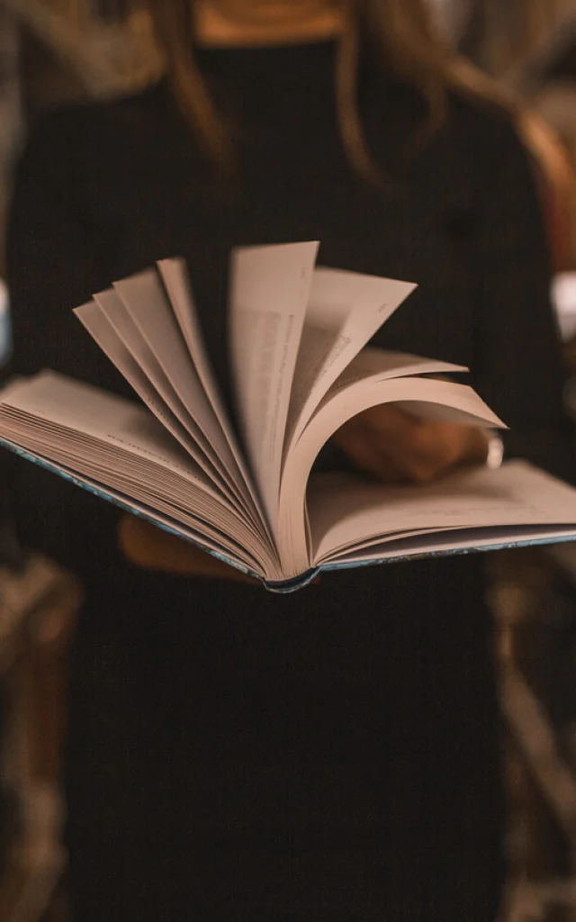 Eine unwiedererkennbare Bibliothekarin hält ein Buch in ihren Händen und blättert die Seiten um