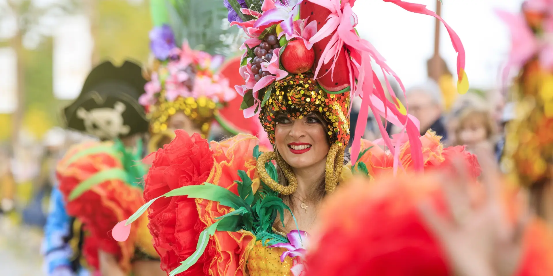 Danseuse costumée à la Fête du Mimosa de Mandelieu sur la Côte d’Azur, vêtue de plumes colorées et de fruits exotiques