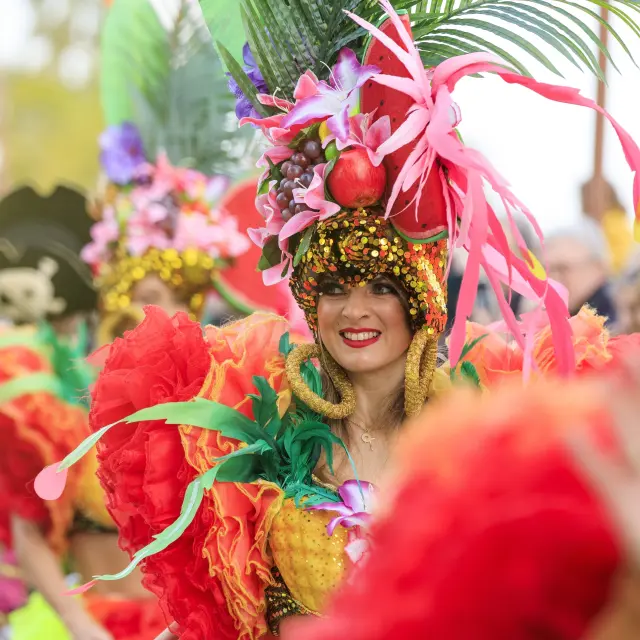 Danseuse costumée à la Fête du Mimosa de Mandelieu sur la Côte d’Azur, vêtue de plumes colorées et de fruits exotiques