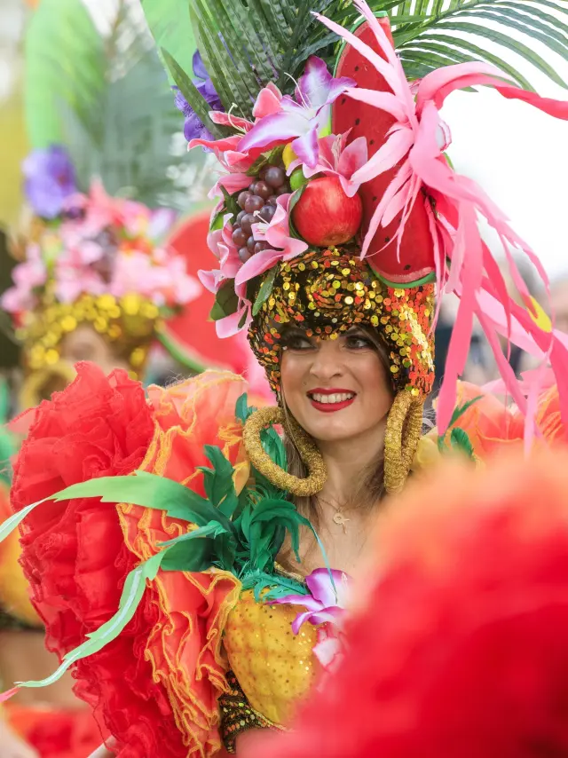 Danseuse costumée à la Fête du Mimosa de Mandelieu sur la Côte d’Azur, vêtue de plumes colorées et de fruits exotiques