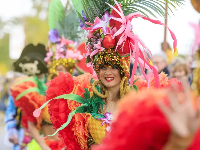 Danseuse costumée à la Fête du Mimosa de Mandelieu sur la Côte d’Azur, vêtue de plumes colorées et de fruits exotiques