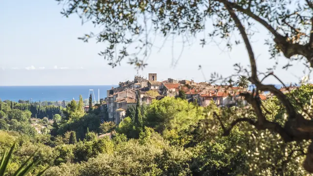 Vue panoramique du village de Biot entouré de végétation avec la mer Méditerranée en arrière-plan.