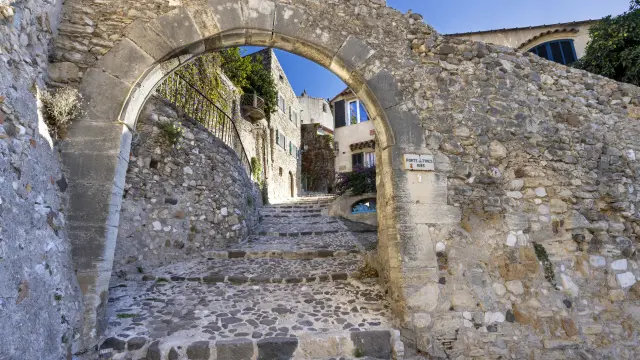 Escalier pavé menant à la Porte des Tines, monument historique de Biot, village perché de la Côte d’Azur entouré de verdure.