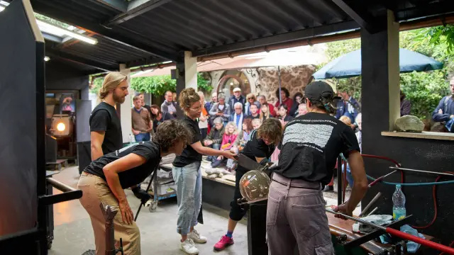 Démonstration de soufflage de verre par des artisans verriers à Biot devant un public captivé.