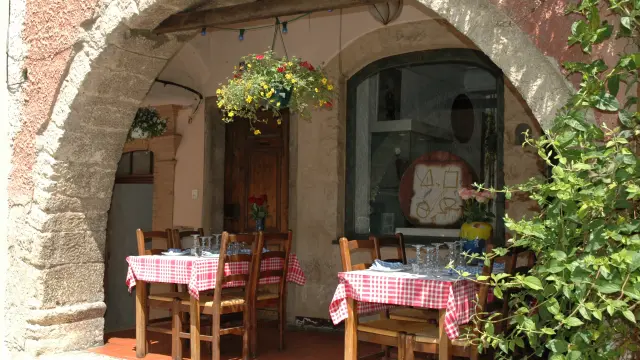 Terrasse de restaurant typique à Biot, avec nappes à carreaux rouges sous une arche en pierre.