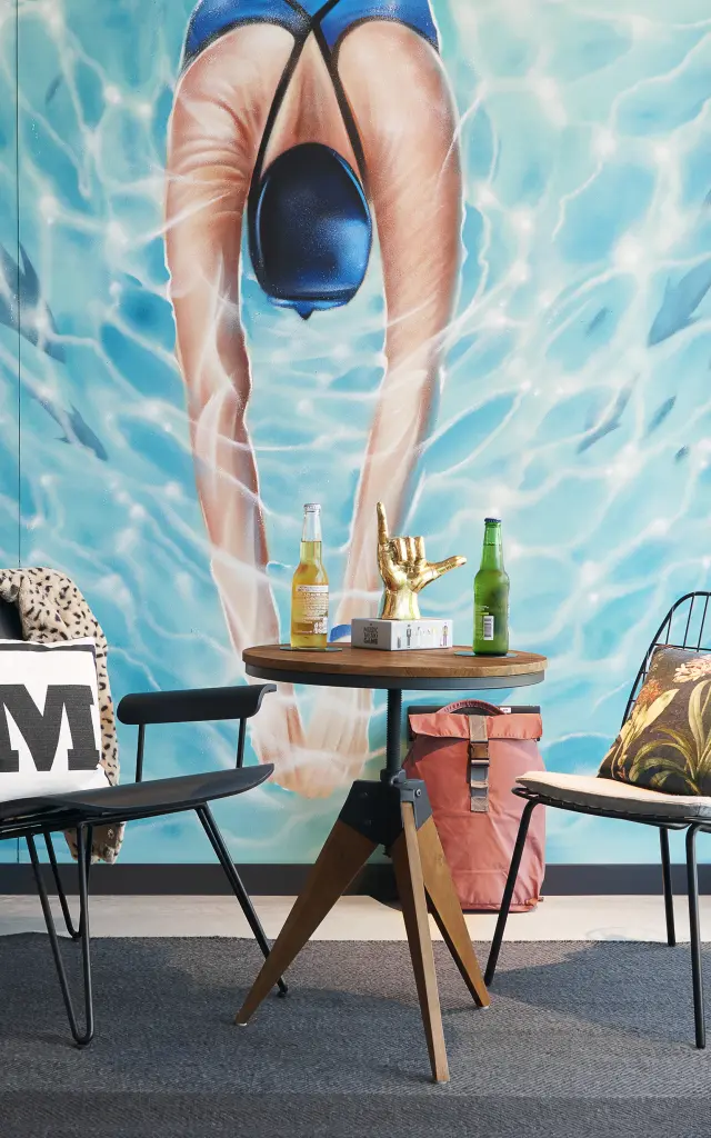 Intérieur design à Biot avec fresque murale représentant une plongeuse et coin détente avec fauteuils et table basse.