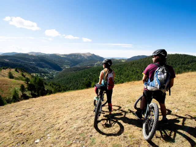Deux vététistes en pause contemplative face aux paysages de montagne à Valberg, dans les Alpes-Maritimes