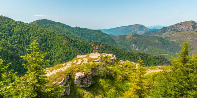 Deux randonneurs sur un promontoire rocheux au Pays des Paillons, face à un panorama de montagnes verdoyantes.