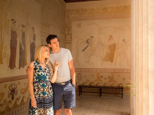 Couple découvrant les fresques d’inspiration grecque dans une salle de la Villa Kérylos à Beaulieu-sur-Mer.
