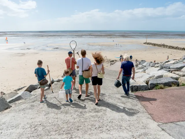 Eine Familie geht auf einem Steinweg zum Strand, um Badminton zu spielen