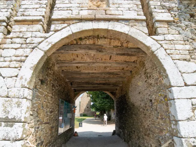 Steinbogen-Durchgang mit einem Fenster darüber und einem Schild auf dem Boden