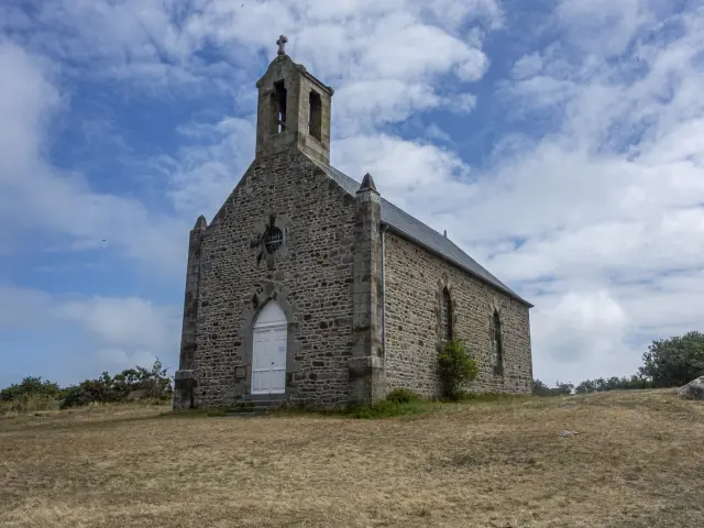 Stone chapel with a pointed steeple and a wooden door