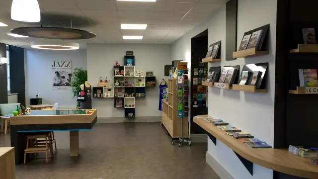 Intérieur d'une boutique avec des étagères remplies de livres et de magazines, et un comptoir en bois