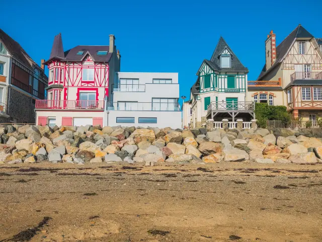 Maisons colorées alignées sur une plage avec des rochers au premier plan