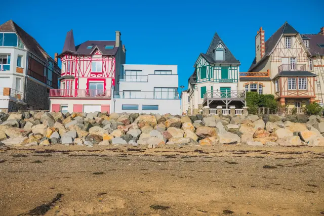 Bunte Häuser in einer Reihe am Strand mit Steinen im Vordergrund