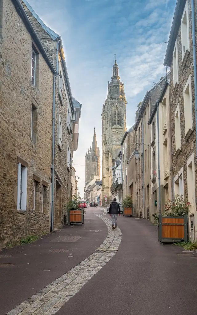 Une rue pavée menant à une cathédrale avec des bâtiments en pierre de chaque côté