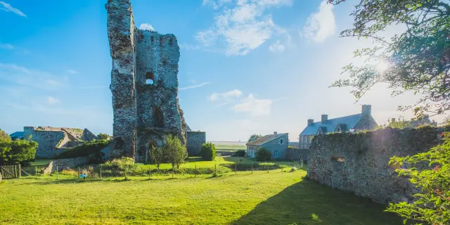 Ruines d'un château médiéval avec des bâtiments modernes à proximité