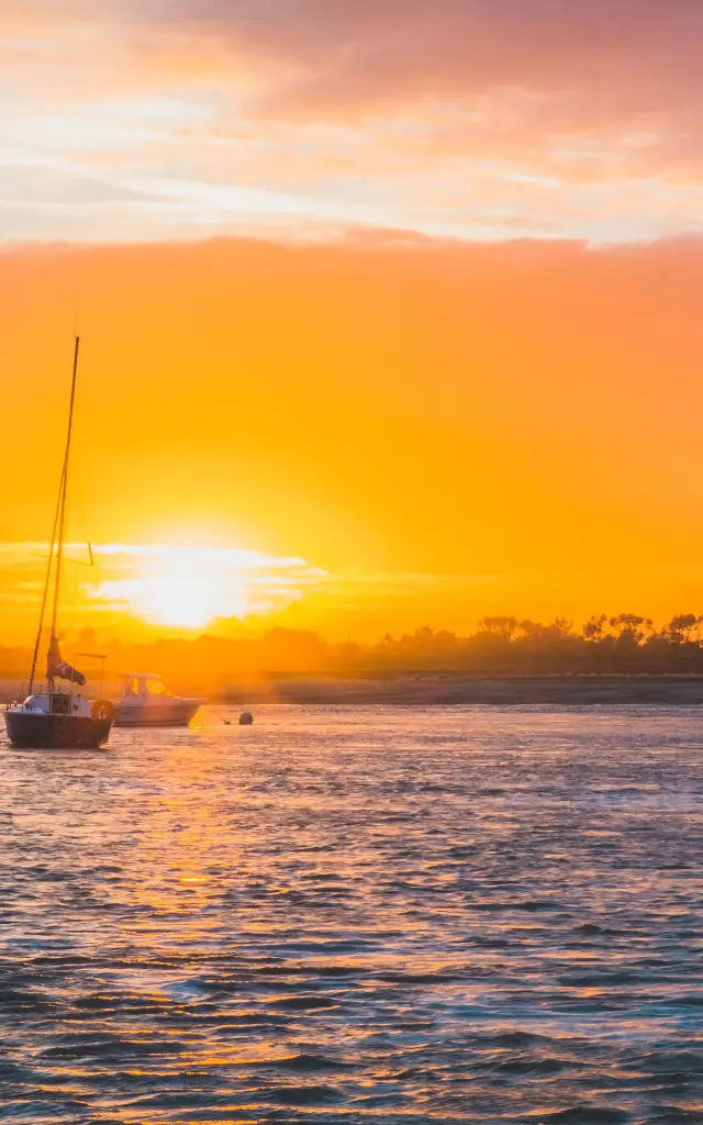 Un bateau à voile sur l'eau au coucher du soleil