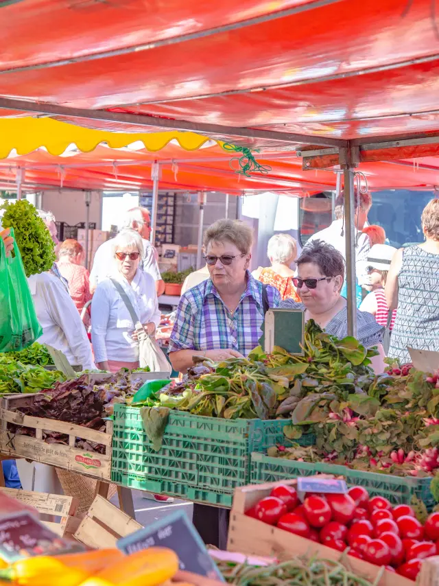Personnes faisant leurs courses dans un marché sous des tentes rouges et jaunes