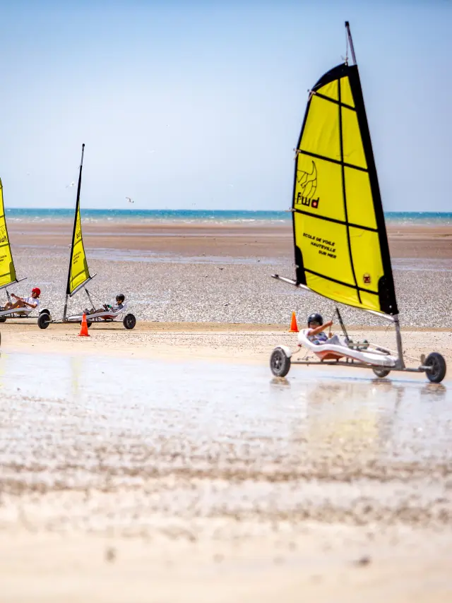 Quatre voiliers sur une plage avec des voiles jaunes et noires