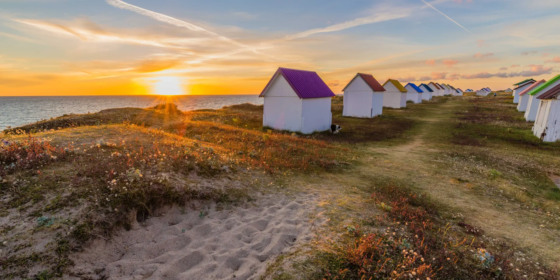 Alignement de cabanes de plage colorées au coucher du soleil