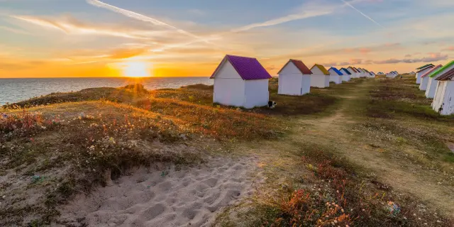 Alignement de cabanes de plage colorées au coucher du soleil