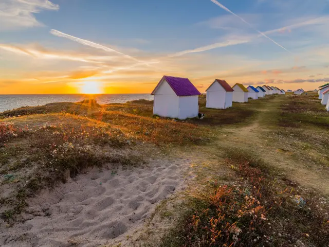 Row of colorful beach huts at sunset