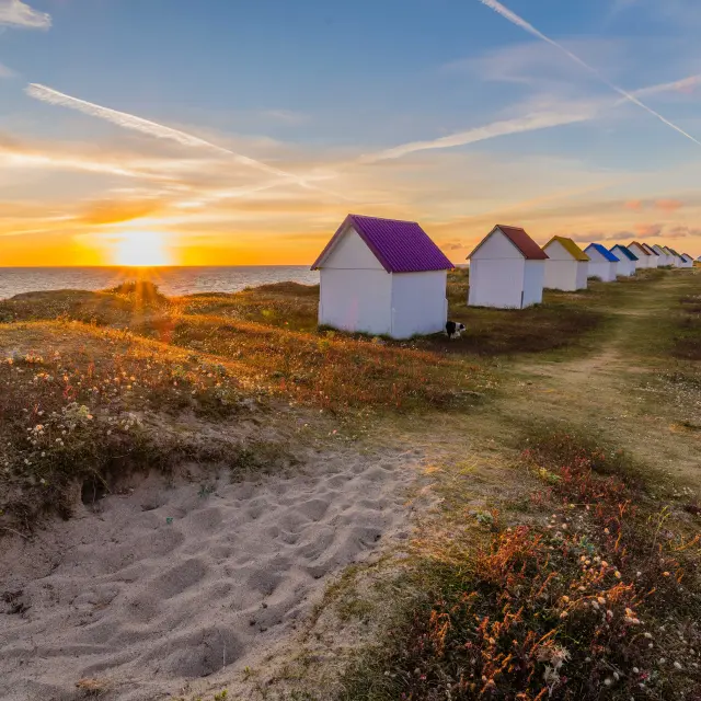 Alignement de cabanes de plage colorées au coucher du soleil