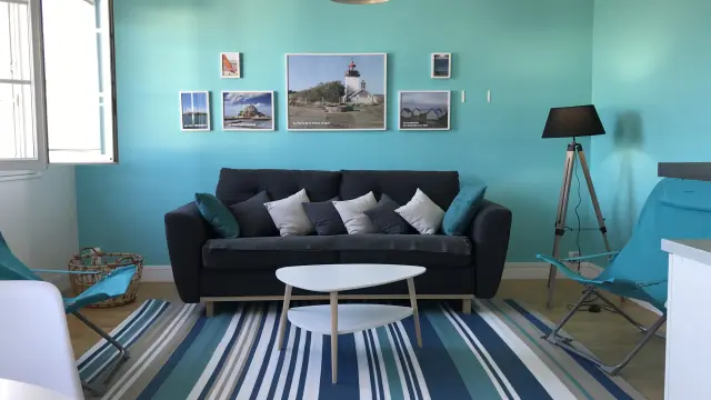 Salon avec canapé noir, table basse blanche, et murs turquoise