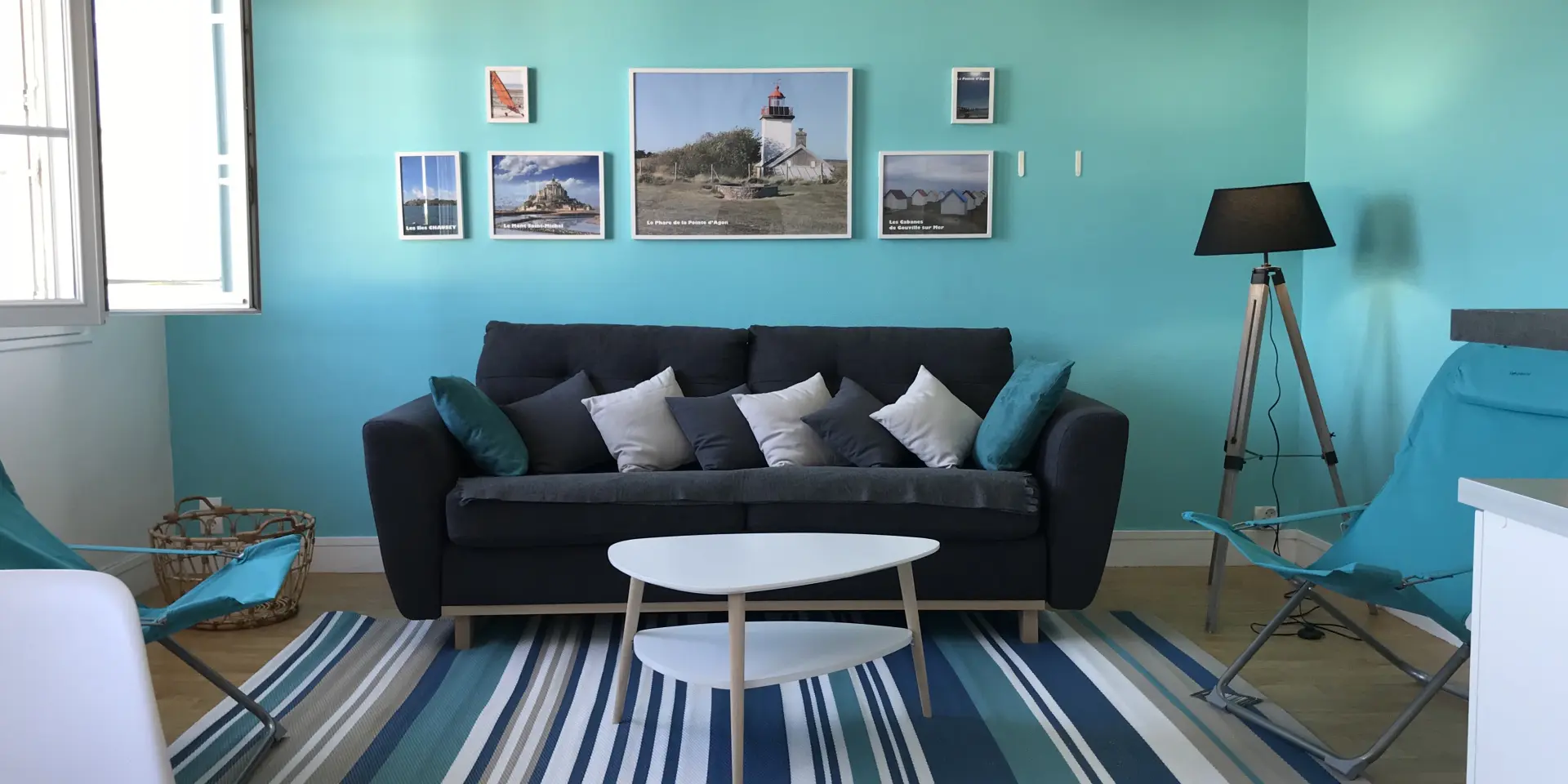 Salon avec canapé noir, table basse blanche, et murs turquoise