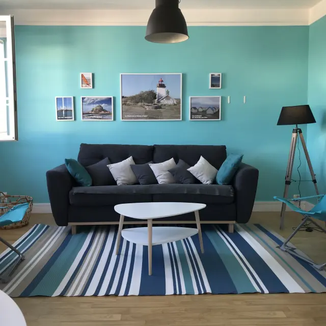 Intérieur d’un salon moderne avec canapé en cuir noir, table basse en verre et vue sur une étendue d’eau depuis une baie vitrée