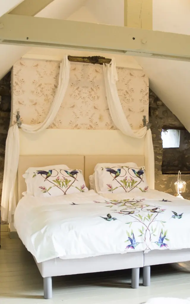 Chambre à coucher avec un grand lit à baldaquin et des murs en pierre apparente