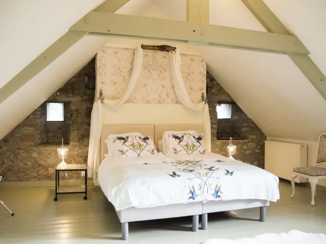 Chambre à coucher avec un grand lit à baldaquin et des murs en pierre apparente