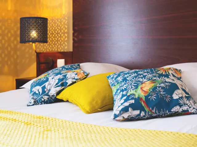 Lit avec des coussins colorés et une lampe de chevet