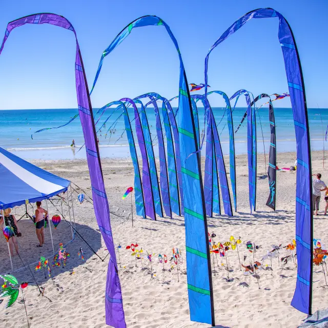 Sailboats moored on a beach with colorful structures in the background