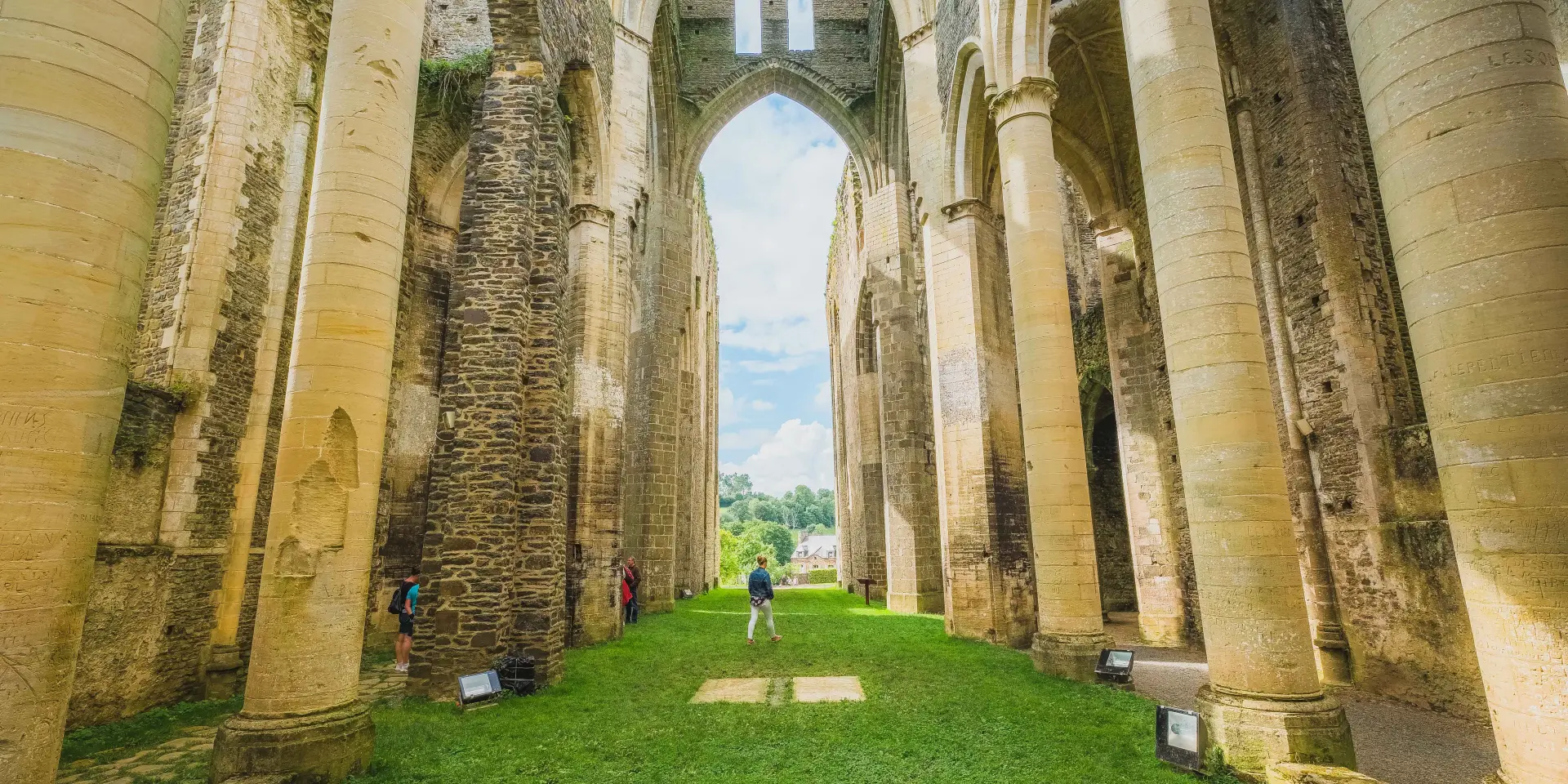 Intérieur des ruines de l'abbaye de Hambye avec des colonnes et de la verdure