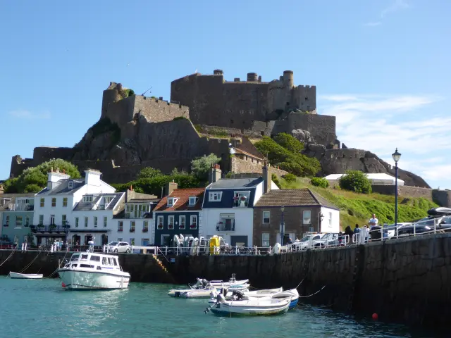 Stone castle on a hill above a harbor with moored boats