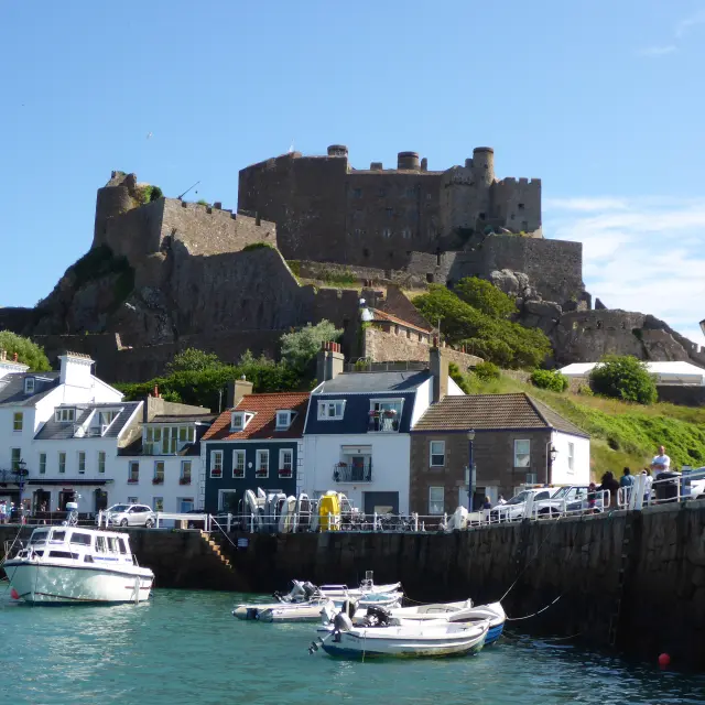 Château en pierre sur une colline au-dessus d'un port avec des bateaux amarrés