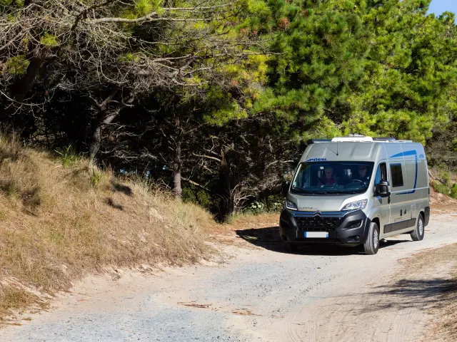 White off-road vehicle driving on a dusty trail in a natural environment