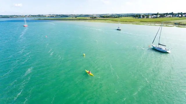 Voiliers amarrés près d’une plage au coucher du soleil avec des bâtiments en arrière-plan
