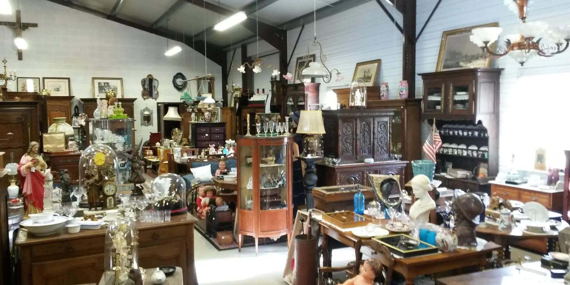 An antique shop filled with old furniture, lamps, and decorative items.
