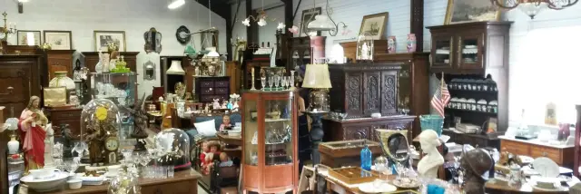 An antique shop filled with old furniture, lamps, and decorative items.