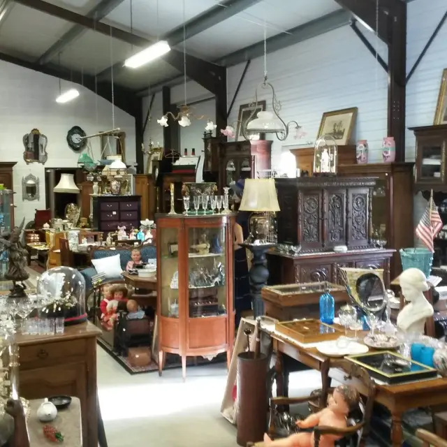 Un magasin d'antiquités rempli de meubles anciens, de lampes et d'objets décoratifs.