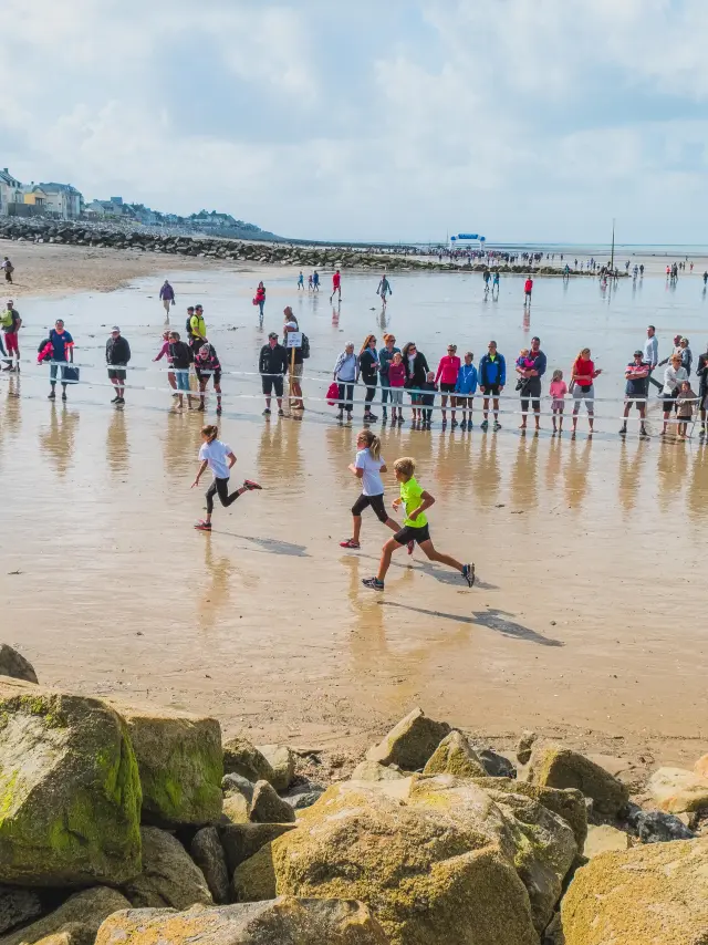 Participants courant sur une plage avec des spectateurs